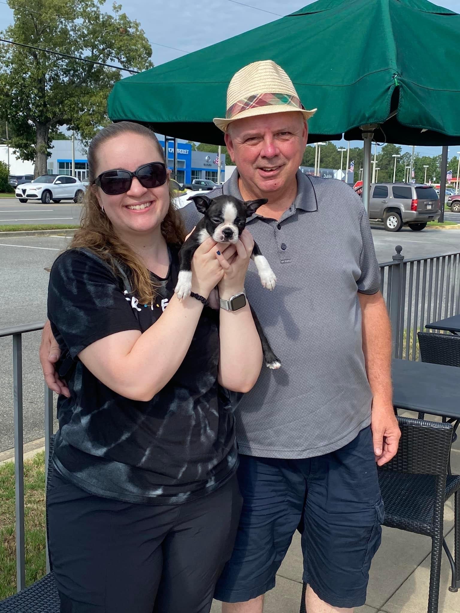Happy family with their new Boston Terrier puppy from Little Paws Boston Terriers.